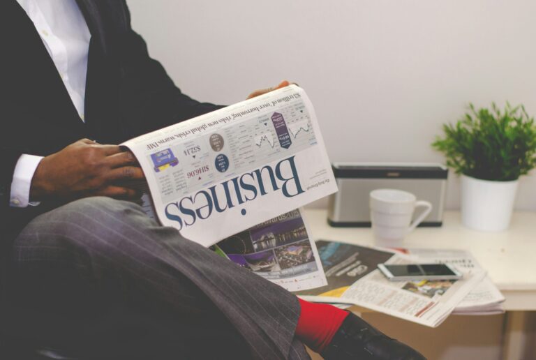 person sitting near table holding newspaper 1 scaled 1 2